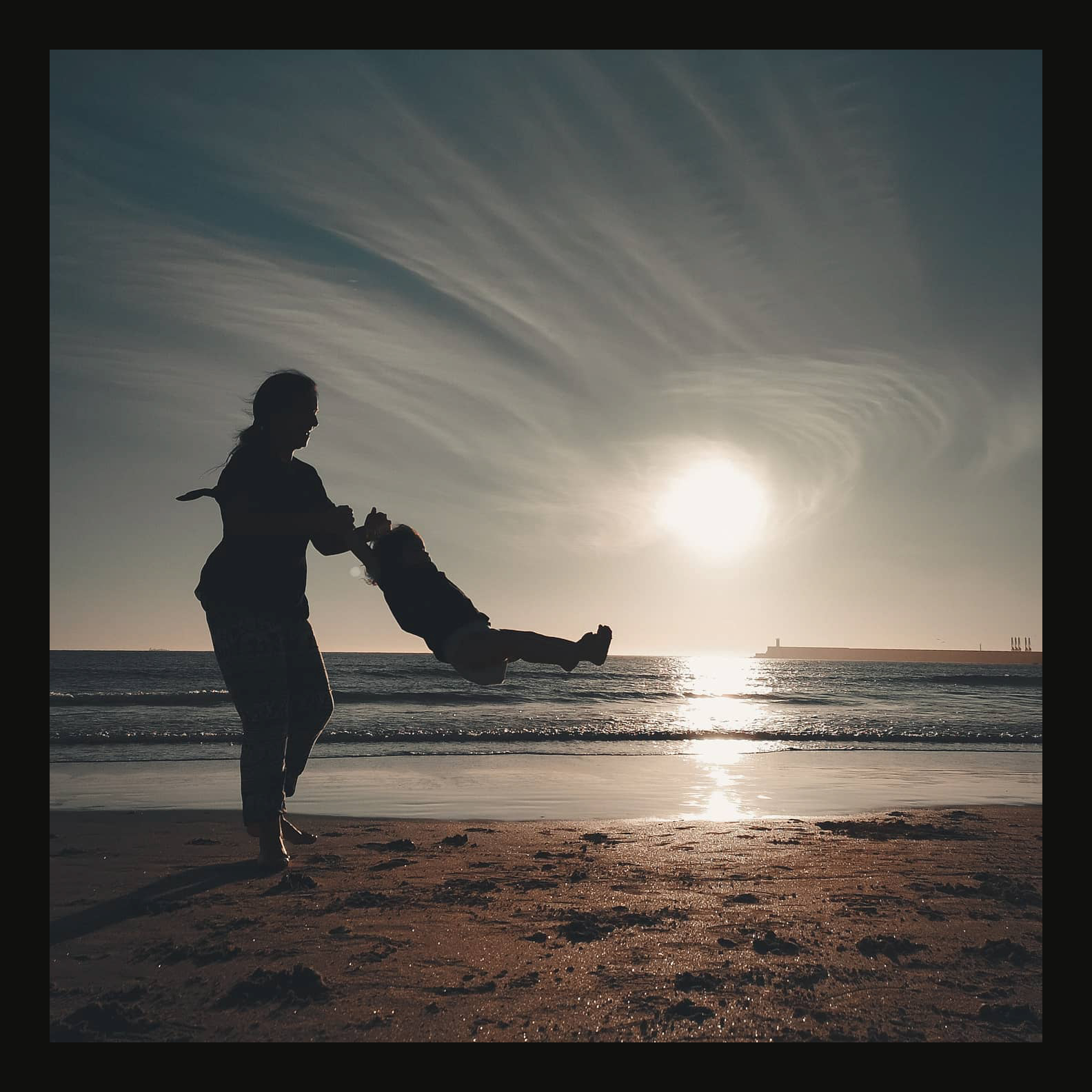 Candid family spinning silhouette on beach